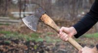 A man holds an ax in his hands against on black background.